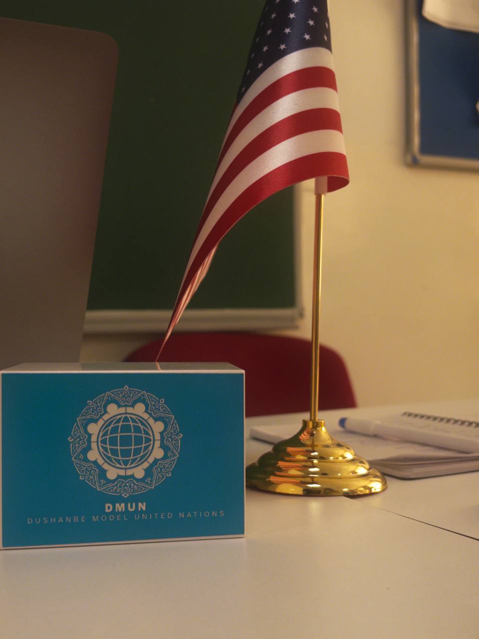 A DMUN branded desk block beside a table flag on a committee desk.