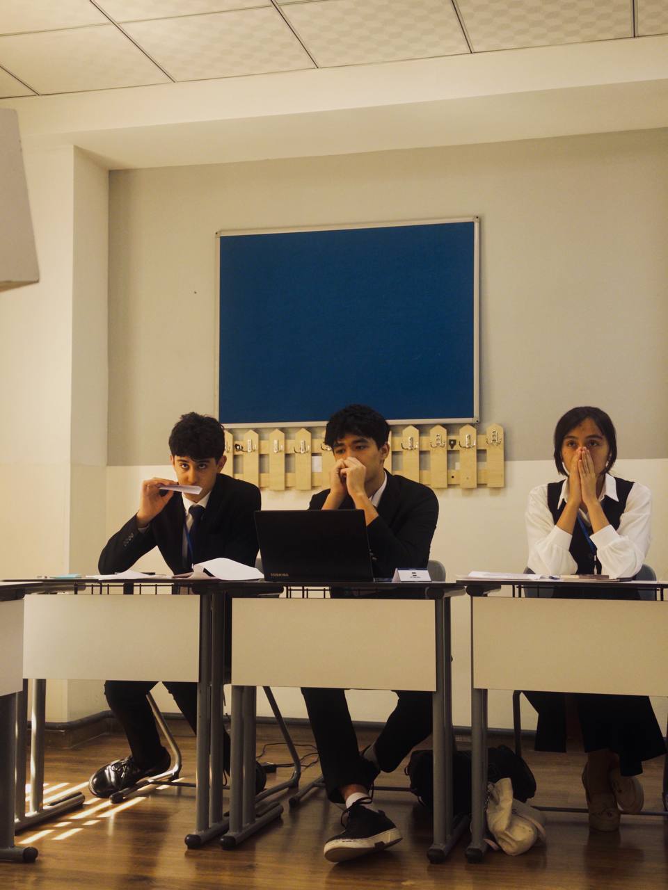 Three delegates seated behind desks listening during a committee session.